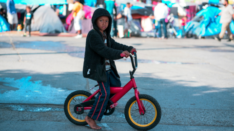 A migrant child on a bicycle